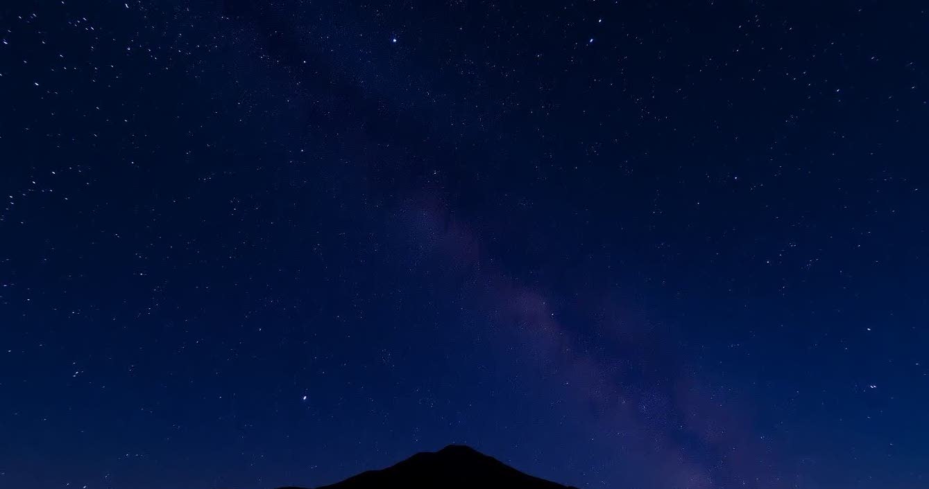 Milky Way and starry sky captured with wide-angle lens over mountain landscape.