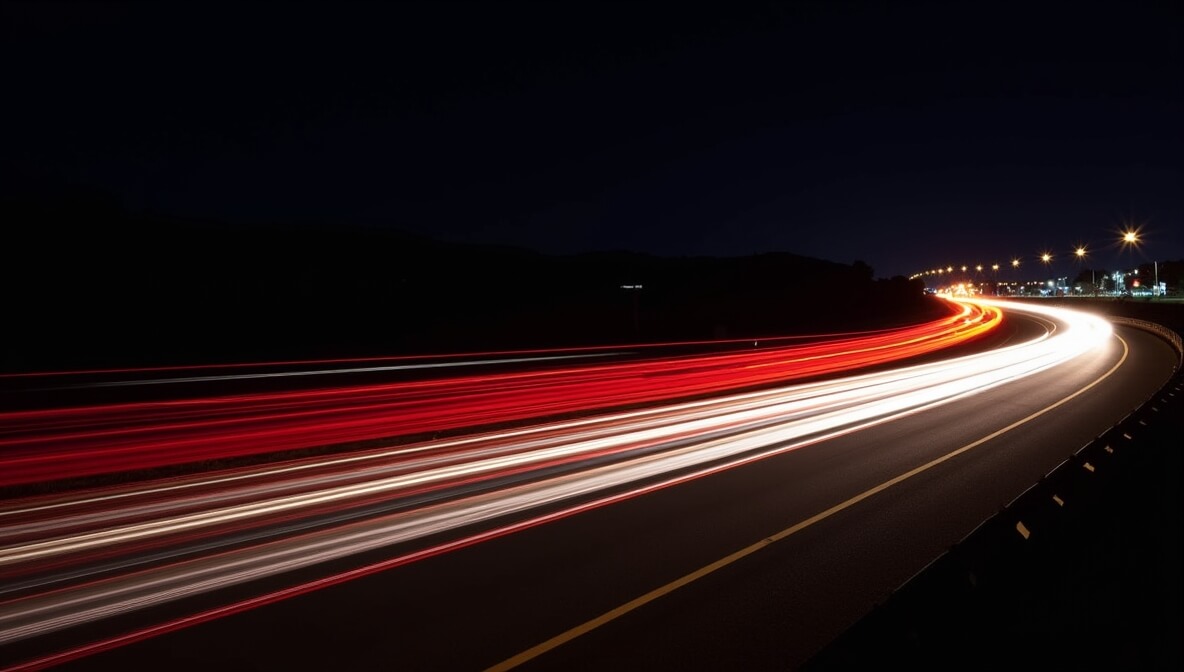 Long exposure photo of car light trails on a highway at night with red and white streaks of light